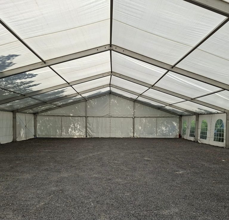 Leeres Großzelt mit grauem Kiesboden Leeres Großzelt von innen mit grauem Kiesboden und weißen Seiten- und Dachplanen.