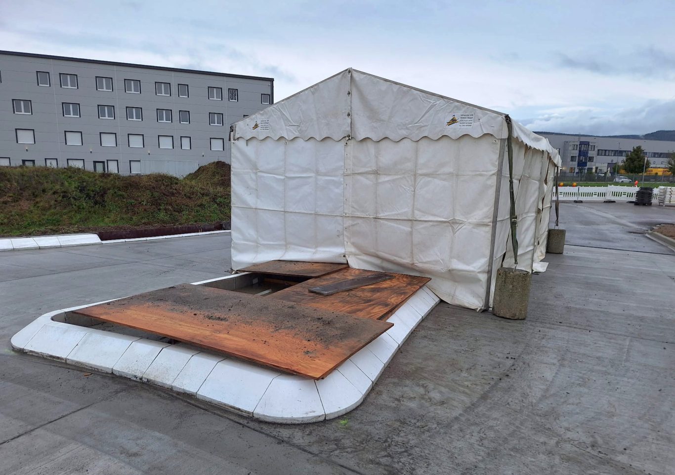 Zelt für Straßenbaustelle Baden-Württemberg Ein temporäres Zelt mit rampe, umgeben von Gebäuden und grauem Himmel.
