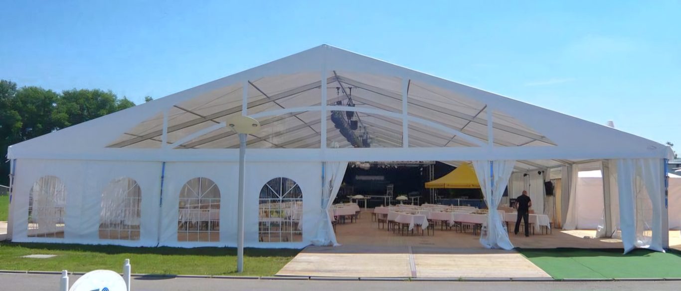 20m Großzelt mit transparentem Giebel Weißes Zelt mit offenen Eingängen und gedeckten Tischen im Innenraum.