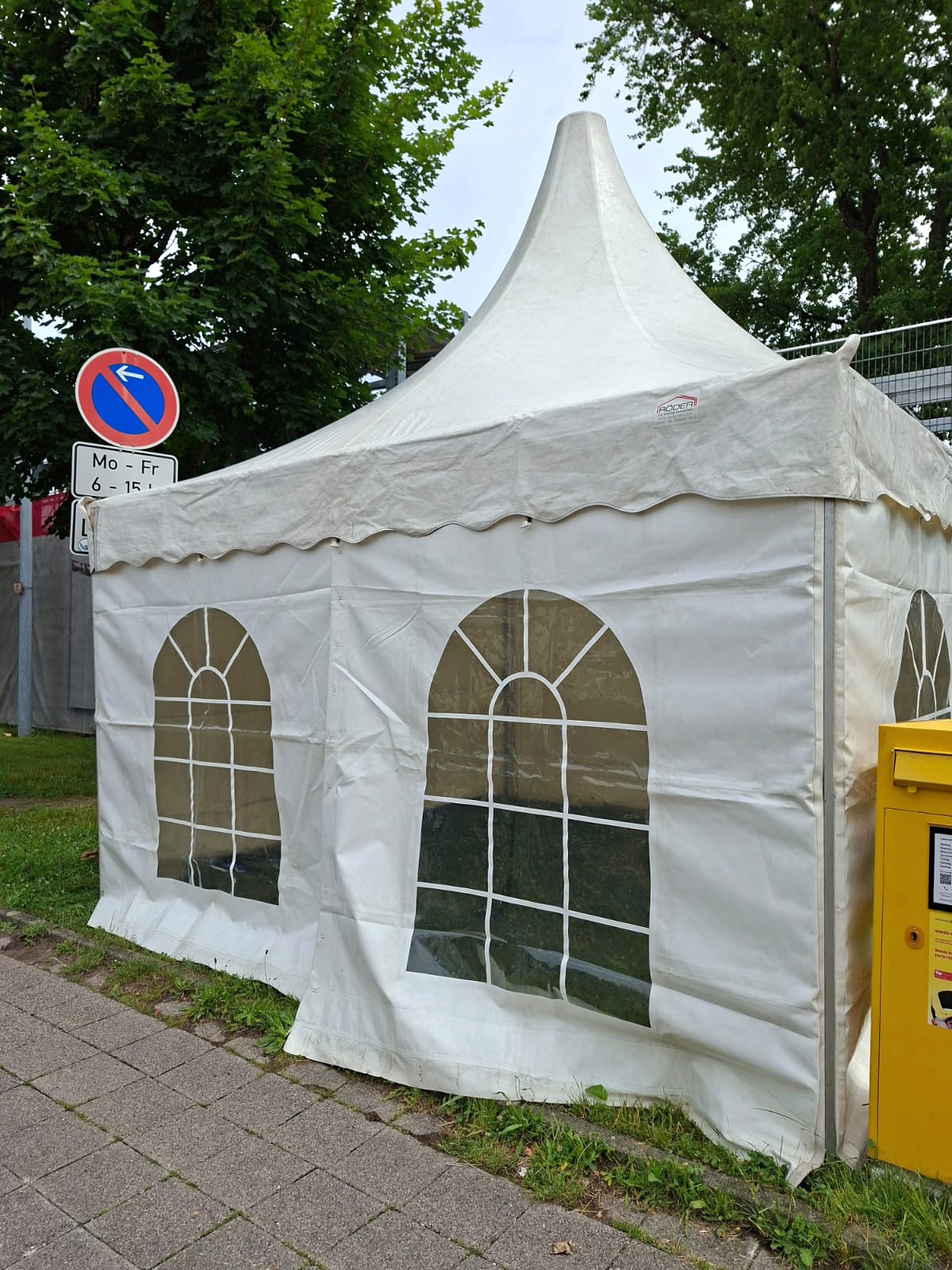 Weißes Pagodenzelt mit Fenster Weiße Pagodenzelt mit Fenster und spitzem Dach, neben einer Straße und einem Postkasten.