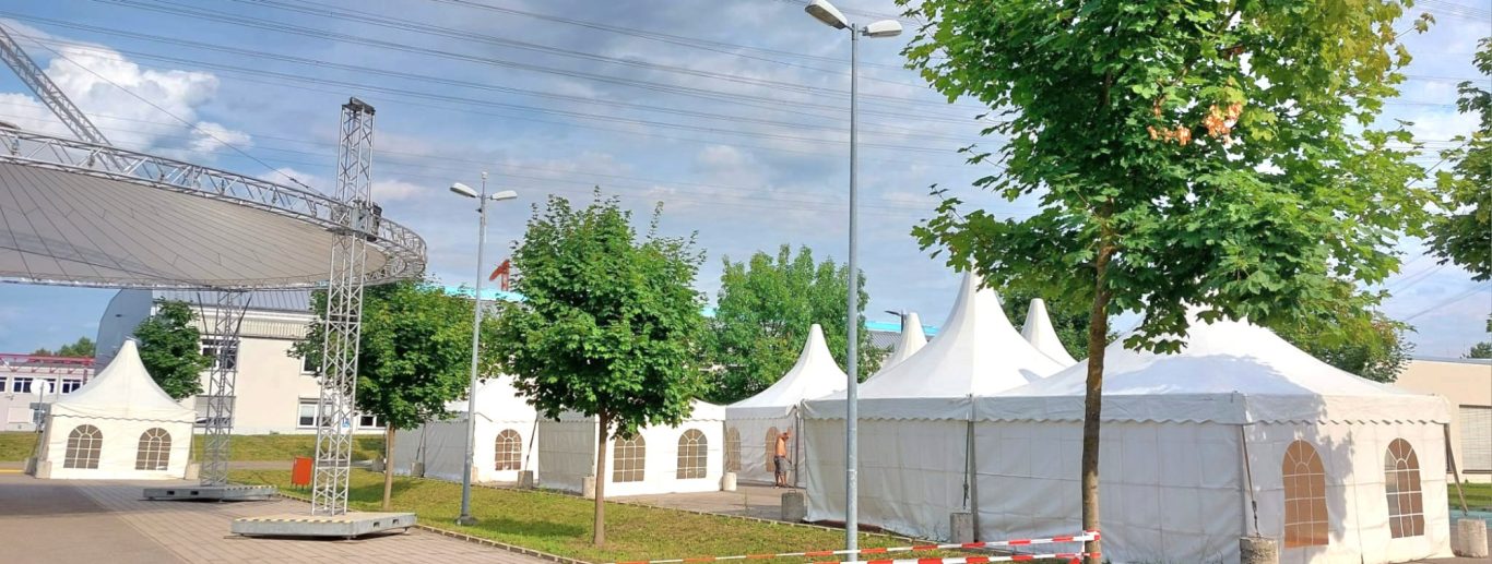 Viele Pagodenzelte für Mitarbeiterfeier Zelte auf einem Platz, umgeben von Bäumen und beleuchtet von Straßenlaternen.