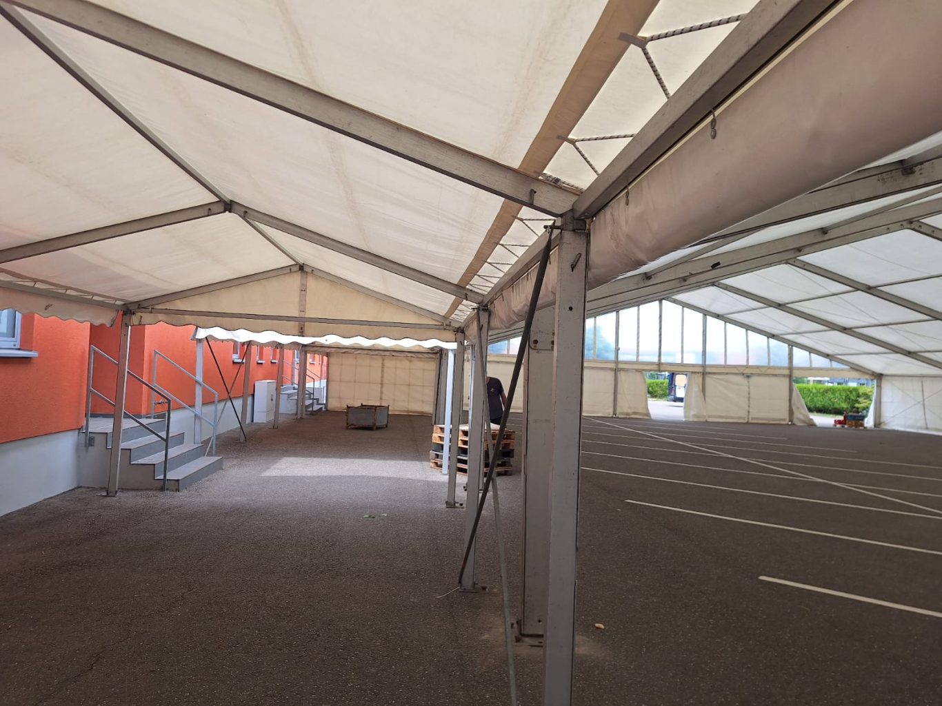 Großes leeres Großzelt Ein großer, leerer Großzeltbereich mit Stützpfosten und grauem Boden.