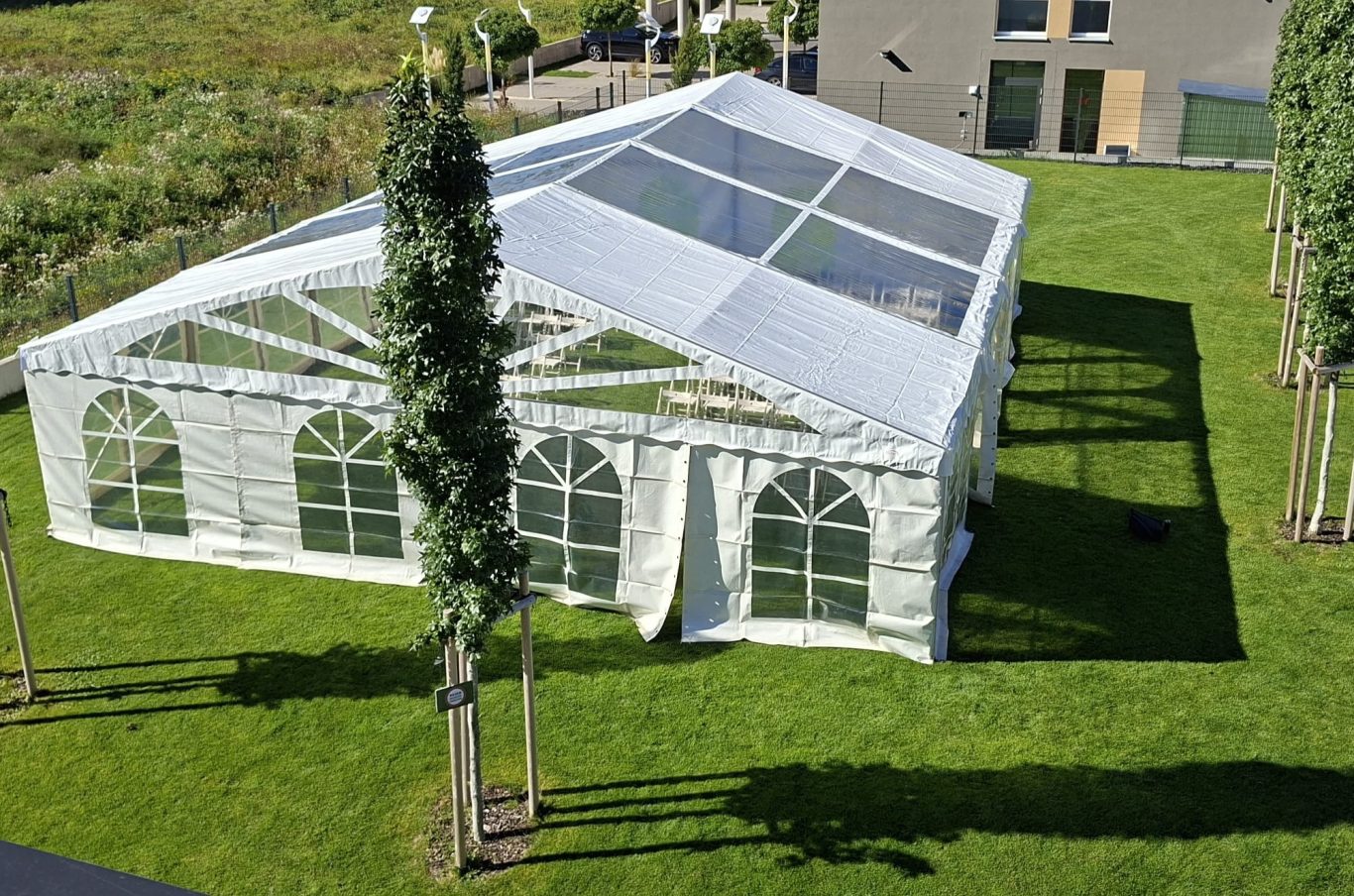 Hochzeitszelt mit transparentem Dach Ein großes Festzelt mit transparentem Dach steht in einem grünen Garten.