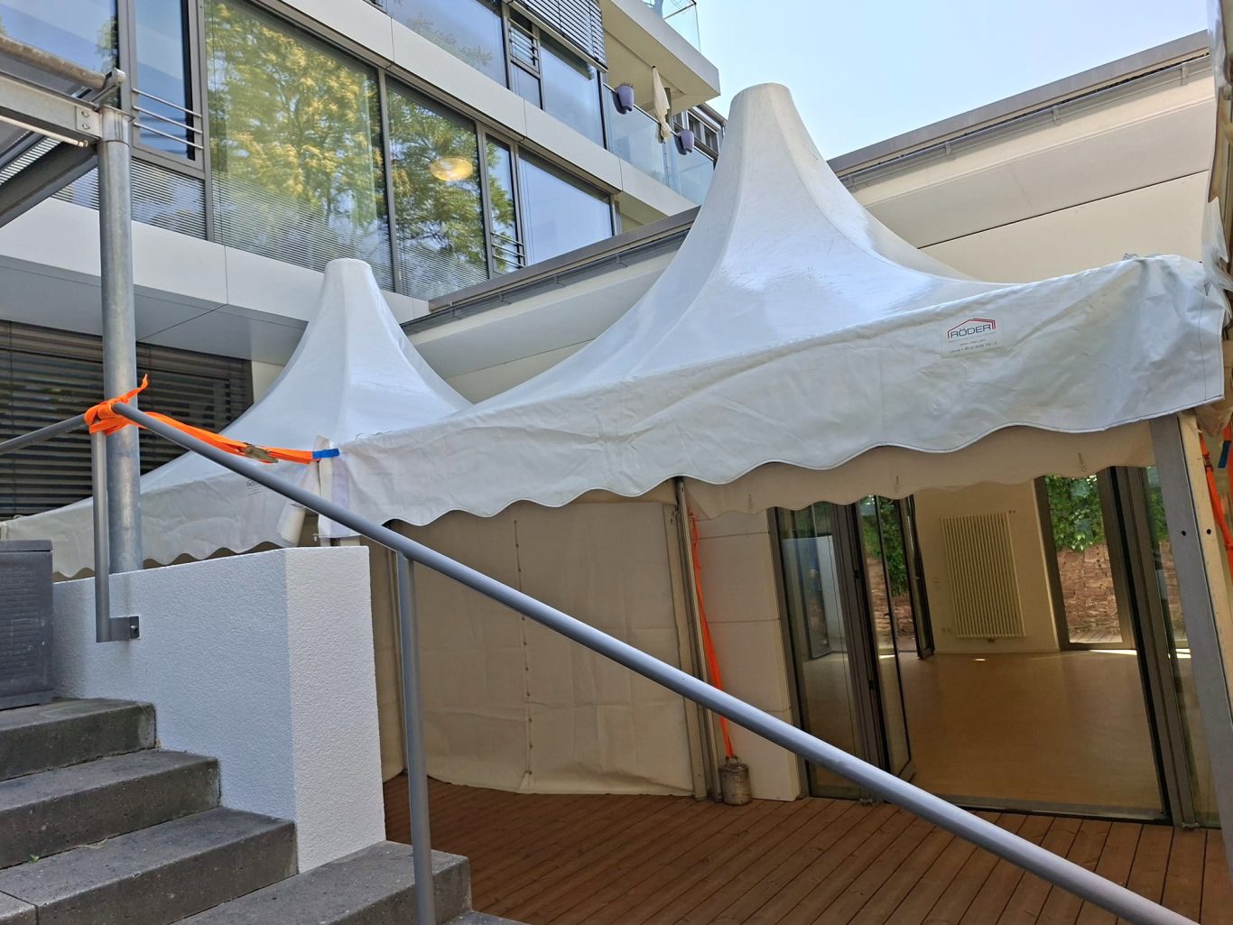 Zwei Pagodenzelte im Eingangsbereich Ein Zeltdach mit Spitzen steht vor einem modernen Gebäude, Treppe darunter.