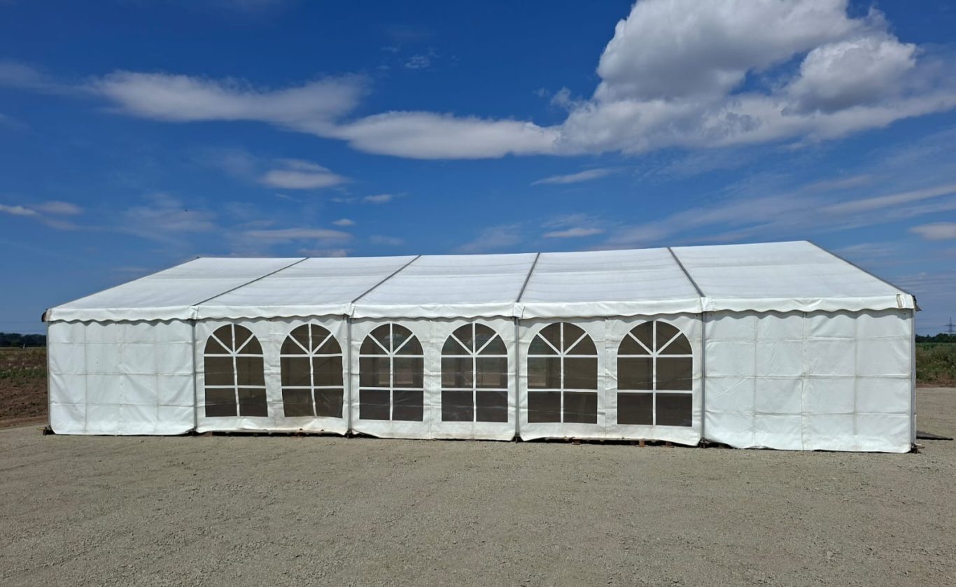 10m x 30m Zelt mit gewölbten Fenstern 10m breites Zelt mit gewölbten Fenstern auf einem weißen Untergrund unter blauem Himmel.