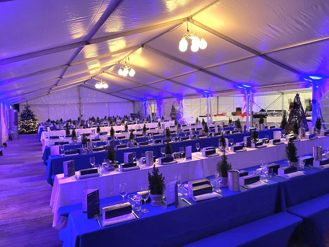Weihnachtsfeier im beheizten Zelt Festlich gedeckter Speisesaal in einem Zelt mit blauer Beleuchtung.