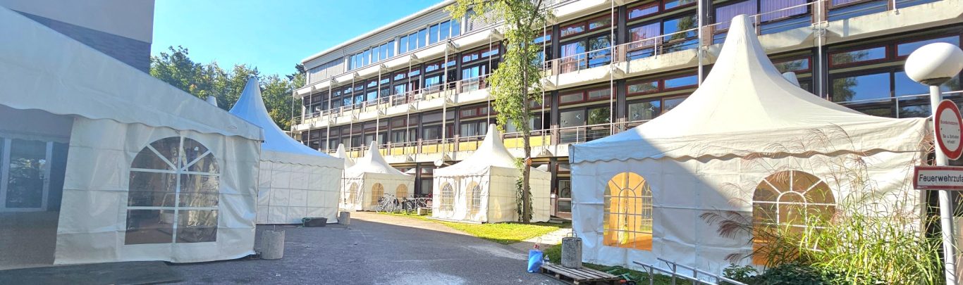 Pagodenzelte Zelte stehen im Freien vor einem modernen Gebäude an einem sonnigen Tag.