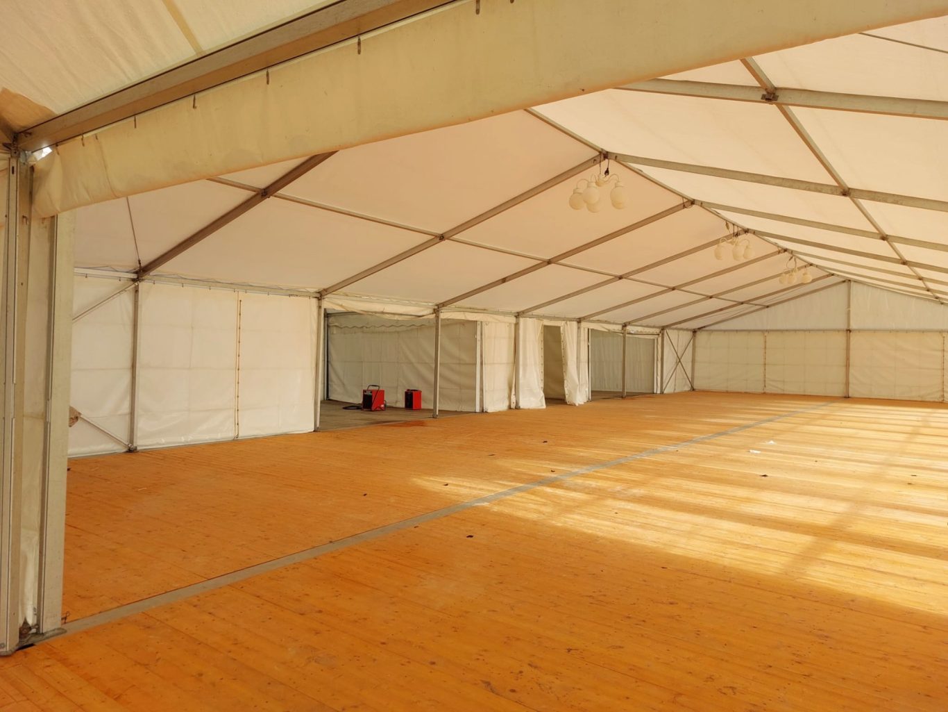 Innenansicht Zelt mit Pagoden im Verbund Großer, leerer Zeltinnnenraum mit Holzboden und weißen Wänden.