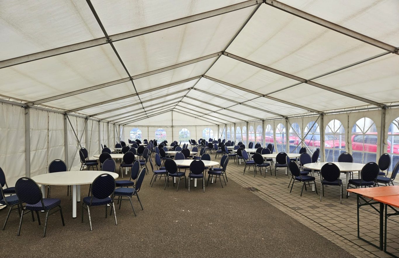 Innenansicht Veranstaltungszelt Innenansicht eines Zeltes mit runden Tischen und Stühlen, bereit für eine Veranstaltung.