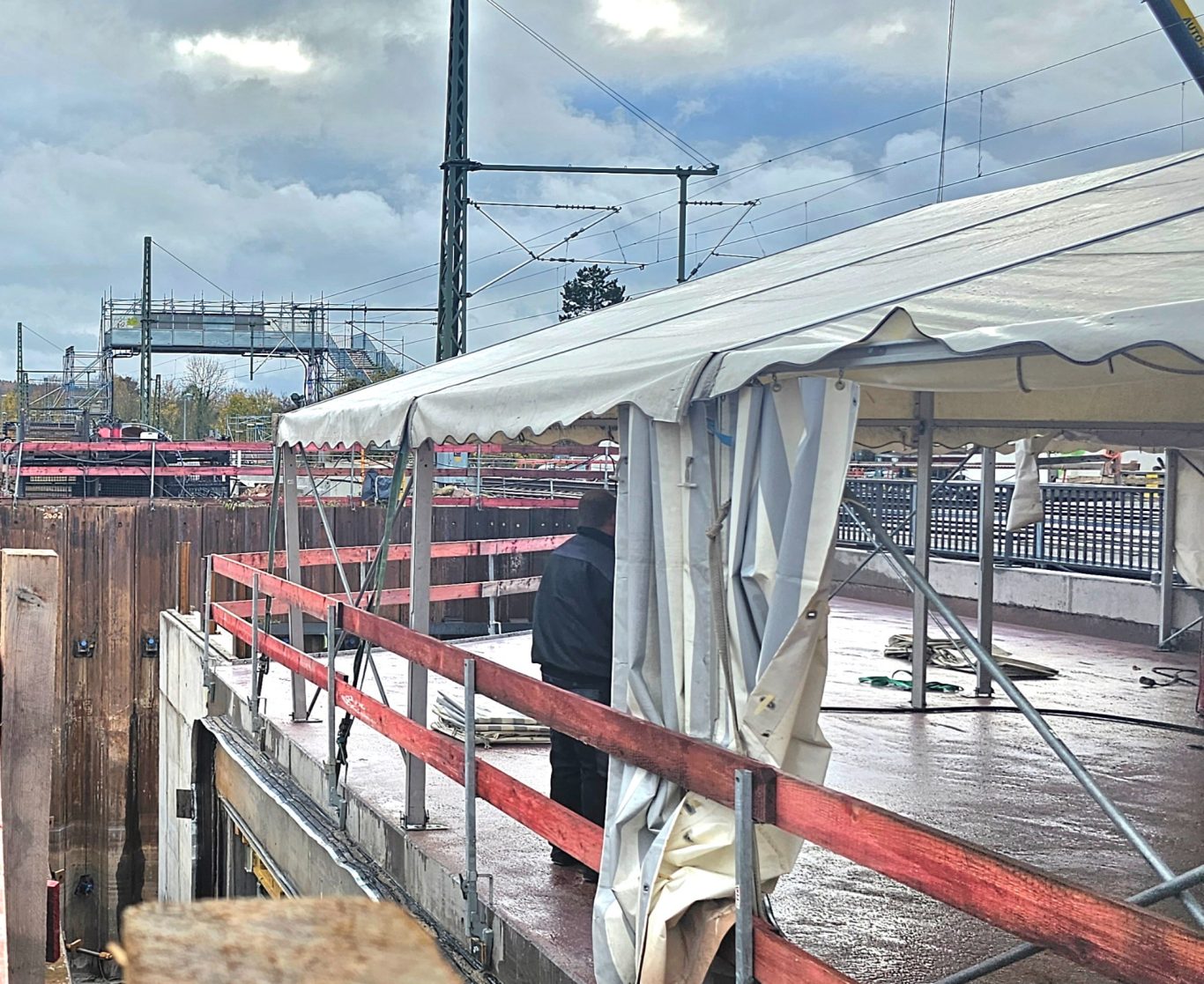 Baustellenzelt auf Brücke Blick auf eine Baustelle mit einem Überdach und Bauarbeiten im Hintergrund.