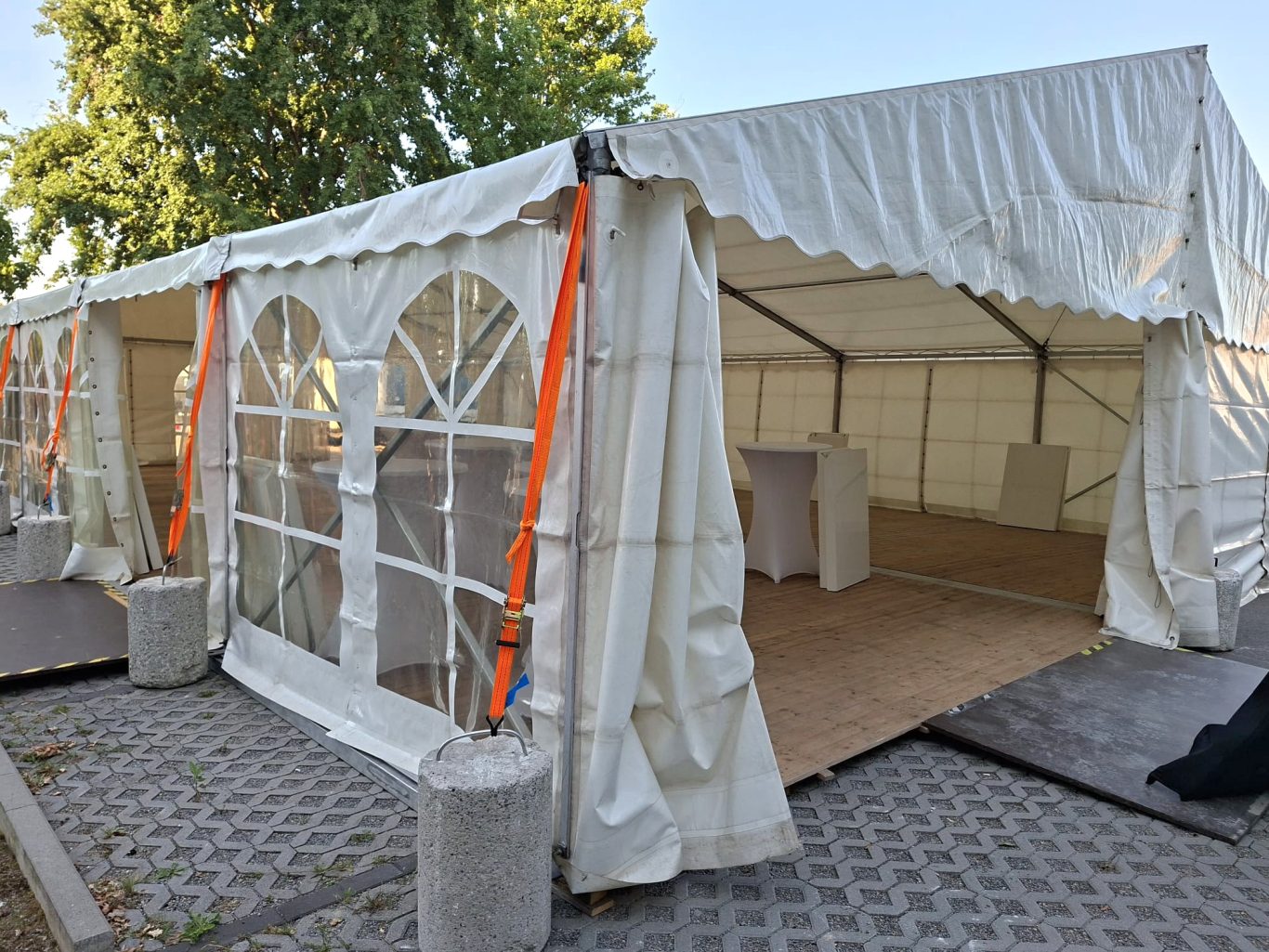 6m breites Zelt mit großen Fenstern Weißes Zelt mit großen Fenstern, auf einem Platz aufgestellt.