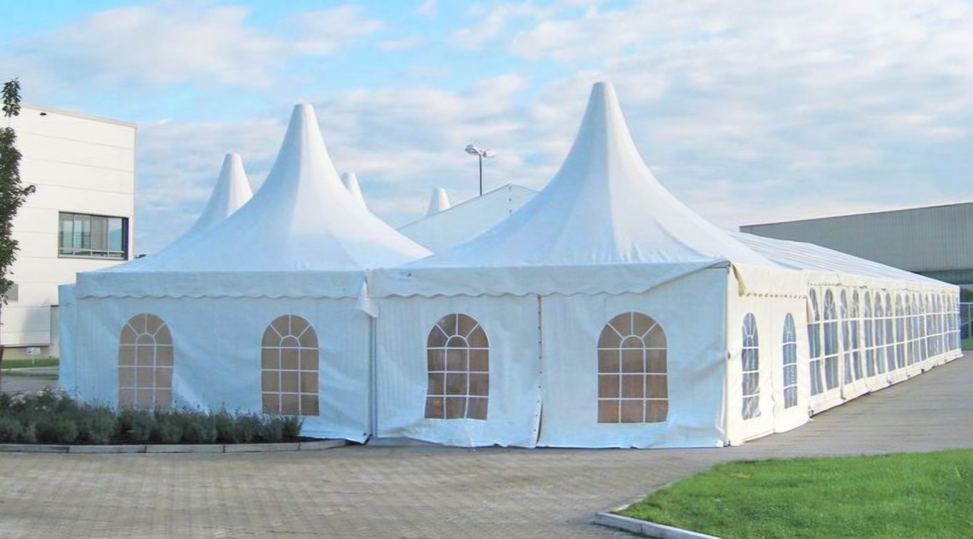 Pagodenzelte mit Festzelt im Verbund Zwei große, weiße Festzelte mit spitzen Dächern und Fenstern im Freien.