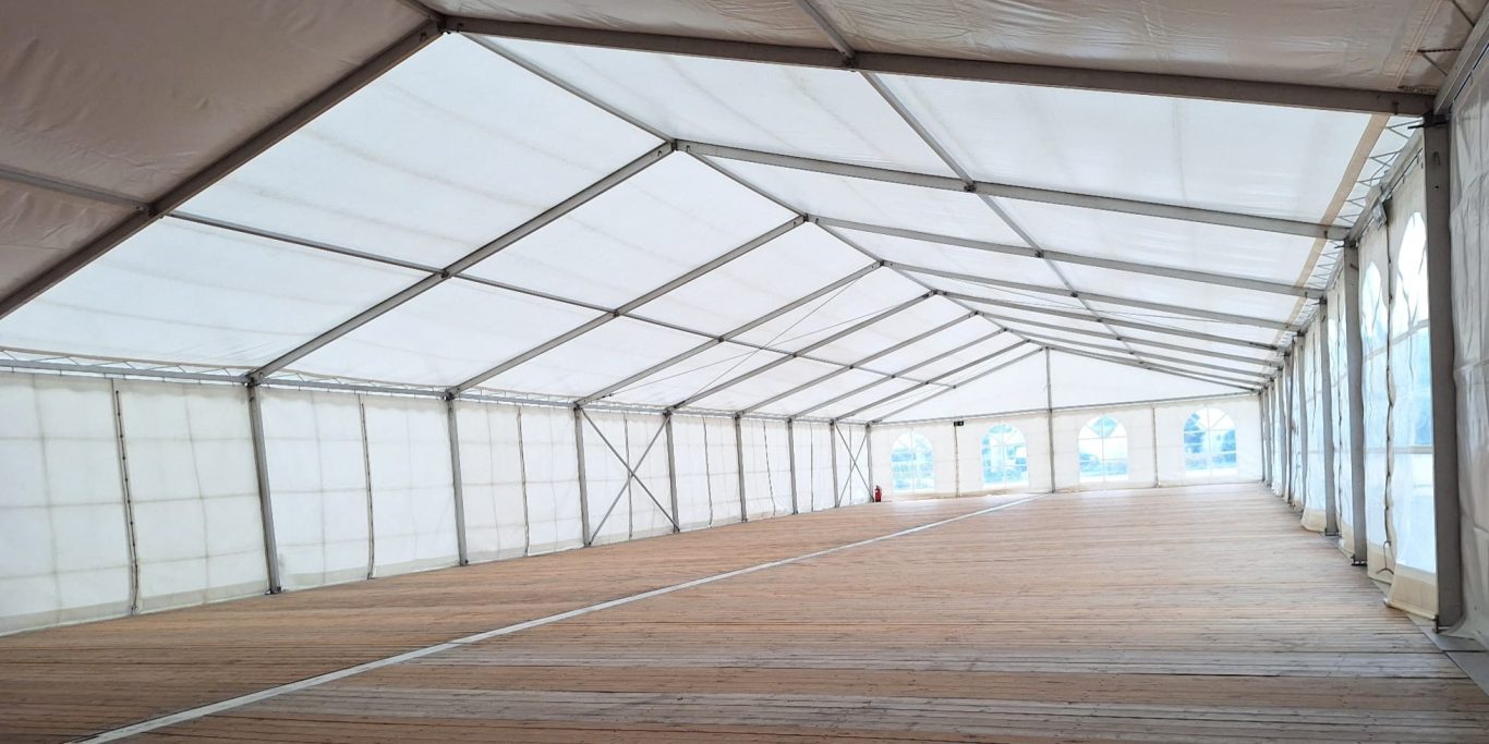 Innenansicht Festzelt mit Holzfußboden Leere Zeltinfrastruktur mit einem geräumigen Innenraum und einem hellen, weißen Dach.