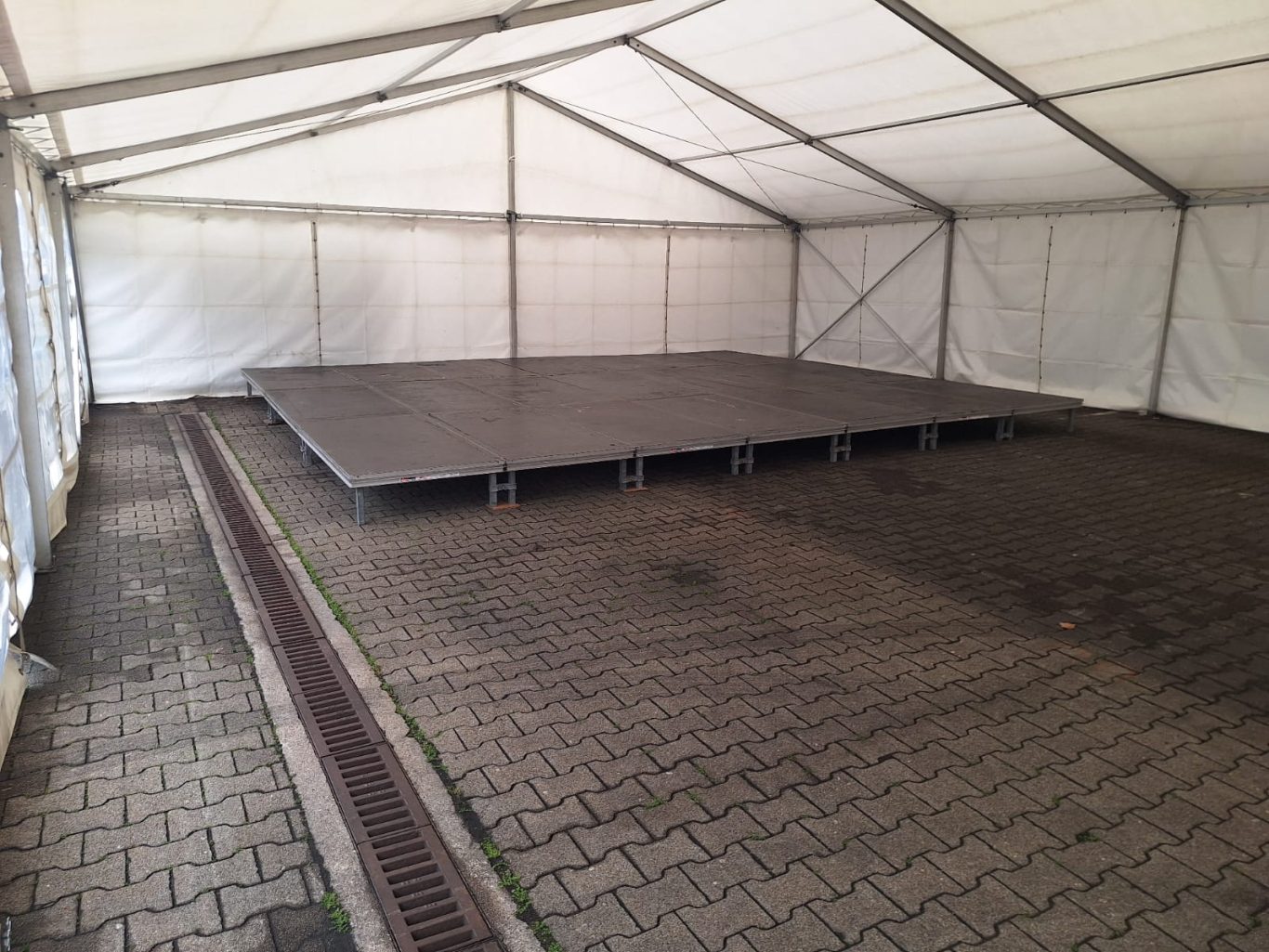 Festzelt Innenbereich mit Bühne Leere Zeltfläche mit einem hohen Podest und gepflastertem Boden.